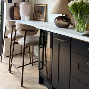 Modern kitchen with wooden shelves, bar stools, and a white countertop.