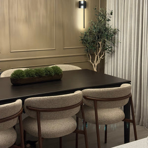 Dining area with chairs, a plant, and decorative wall lights.