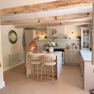 Modern kitchen with wooden beams and a woman at the counter.