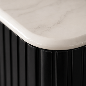Close-up of a modern black ribbed cabinet or sideboard with a white marble-look top surface.